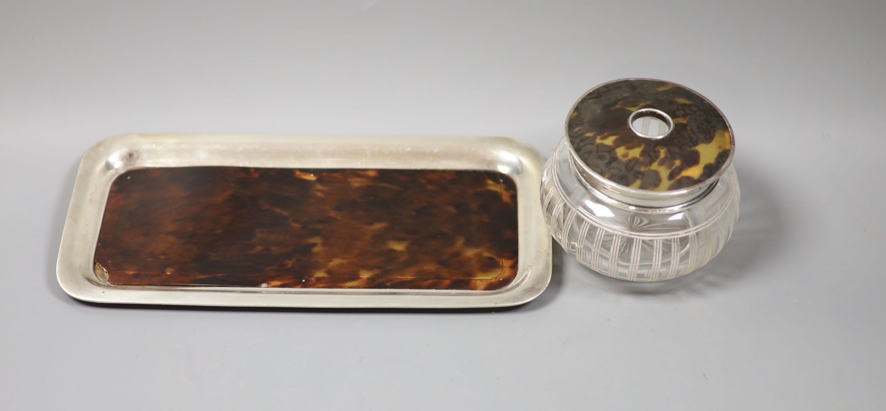 An Edwardian silver mounted tortoiseshell dressing table tray and a similar mounted glass tidy.